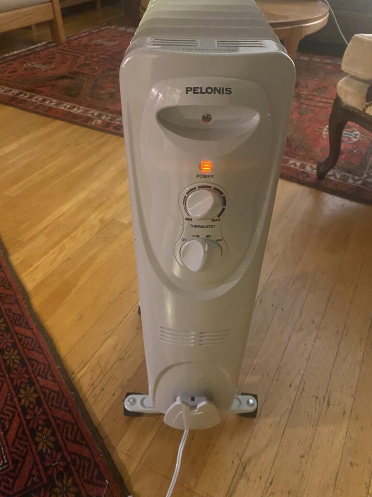 PELONIS oil filled radiator heater review — front view of the PHO15A2AGW with power light on and analog thermostat dial