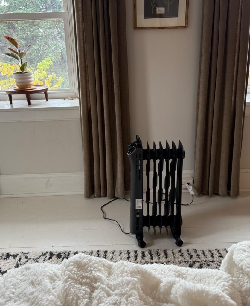 Oil-filled radiator heater by a window — Amazon Basics black 7-fin heater set up in a room
