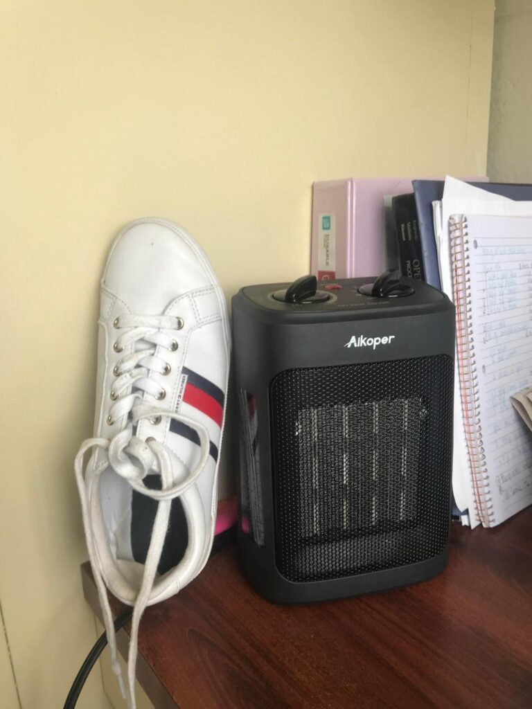 Compact Aikoper space heater on a desk next to a shoe for size comparison