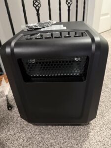 Portable infrared space heater on carpet with remote resting on top