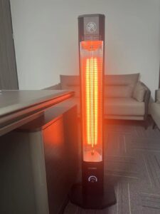 HAIMMY UEH520 infrared tower heater glowing orange indoors beside a sofa and table