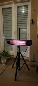 Paraheeter QHA-15DB infrared patio heater on tripod at night, glowing heating element with H1 display