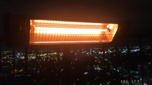Heat Storm infrared heater glowing orange at night, with city lights in the background