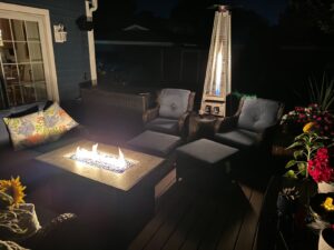 Cozy outdoor deck setup with chairs and a fire table, plus a FOOWIN pyramid patio heater glowing in the background at night