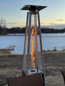 Close-up of a Pamapic pyramid flame patio heater with tall glass tube showing a vertical propane flame outdoors