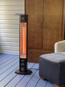 HAIMMY UEH520 electric infrared patio heater running on a porch deck next to an ottoman