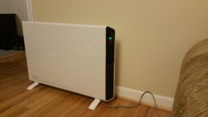 De’Longhi SlimStyle panel heater freestanding against a wall in a room, display set to 78°F