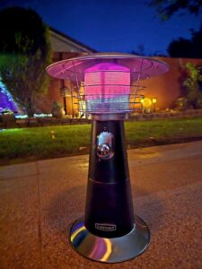 Cuisinart tabletop propane patio heater running at night on an outdoor patio, radiant burner glowing bright pink and red