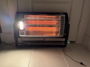 Close-up of Shinic radiant quartz heater running indoors, orange heating tubes glowing with side work light