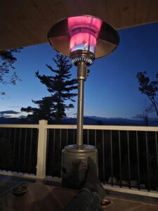 Amazon Basics 46,000 BTU propane patio heater glowing on a deck at dusk with a mountain view