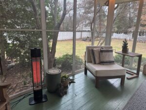 Encyclpo infrared tower heater warming a screened porch beside a lounge chair and side table.
