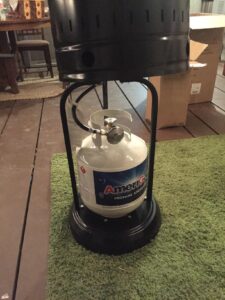 Propane tank connected inside the patio heater base, showing regulator and hose connection