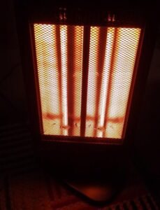 Comfort Zone halogen space heater glowing orange while running in a dark room