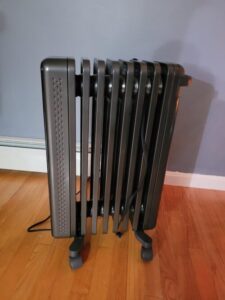 Side view of the Dreo DR-HSH011 oil-filled radiator heater showing its 8-fin design and caster wheels