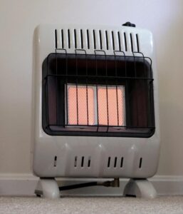 Mr. Heater F299811 vent-free radiant natural gas heater glowing on carpeted floor in a room