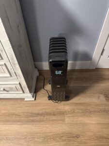 Dreo oil-filled radiator heater with digital thermostat set to 68°F in a bedroom corner