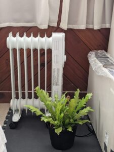Comfort Zone CZ7007J portable oil-filled radiator heater placed near curtains and furniture in a small room
