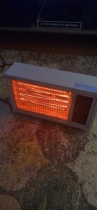 Homeleader radiant space heater turned on in a dim room, showing bright heating elements on a carpeted floor