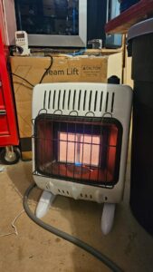 Mr. Heater F299811 radiant natural gas heater in a garage workshop with hose connected