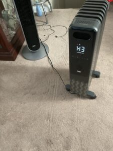 Dreo oil-filled radiator heater running on H3 high heat setting in a carpeted living room