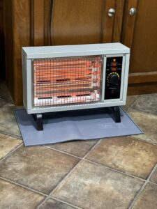 Homeleader electric radiant heater in use on a floor mat in a kitchen, with glowing elements and manual thermostat controls