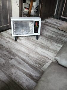 Homeleader portable radiant heater placed on a vinyl floor in an RV-style interior, showing full unit size and placement